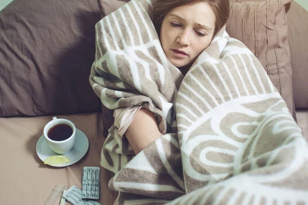 young woman sick with a cold lying in bed