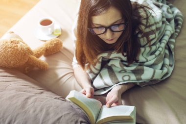 Kadın bir sıcak battaniye okuma kitapta sarılmış