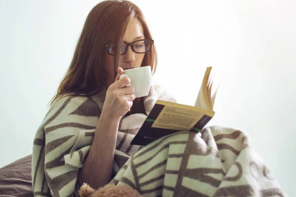 Donna avvolta in un caldo libro di lettura coperta — Foto Stock