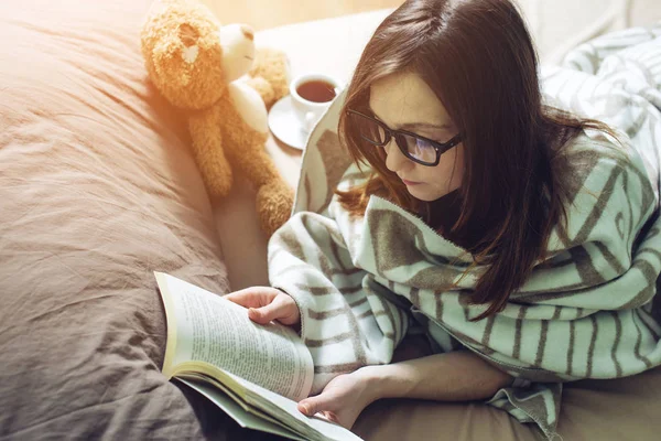 Femme enveloppée dans un livre de lecture de couverture chaude — Photo