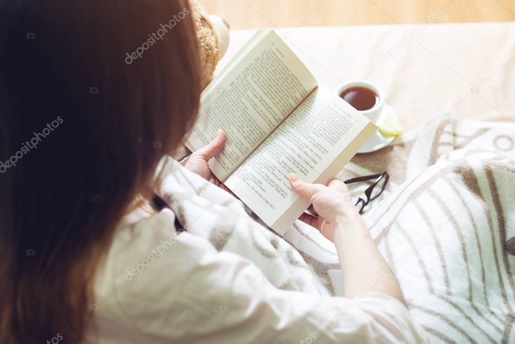 Woman wrapped in a warm blanket reading book