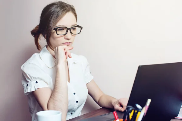 Chica atractiva con las gafas de escribir en un ordenador portátil — Foto de Stock