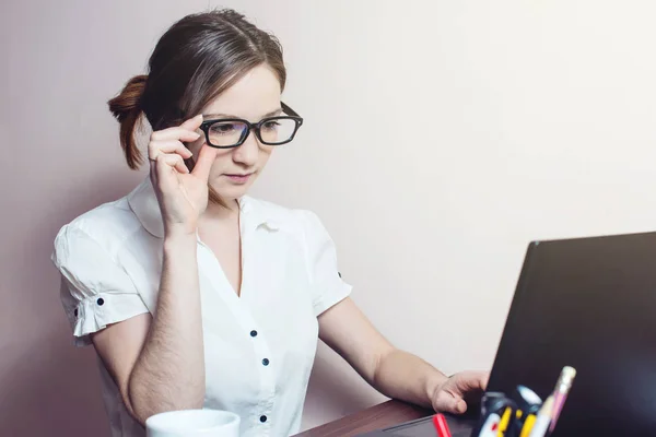 Chica atractiva con las gafas de escribir en un ordenador portátil — Foto de Stock