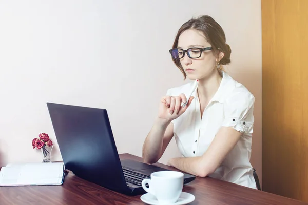 Chica atractiva con las gafas de escribir en un ordenador portátil — Foto de Stock