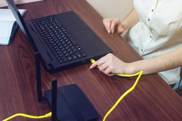 woman connect Internet cable to connector on the laptop