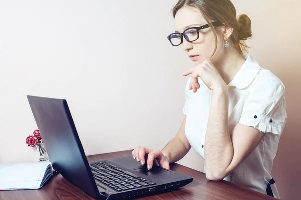 Chica atractiva con las gafas de escribir en un ordenador portátil — Foto de Stock
