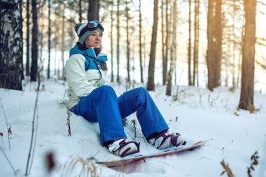 Kadın Snowboard snowboard ile kar üzerinde oturmuş dinleniyor