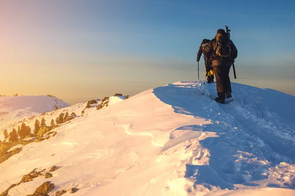 Karlı dağlardaki dön günbatımında seyahat yürüyüşçü — Stok fotoğraf