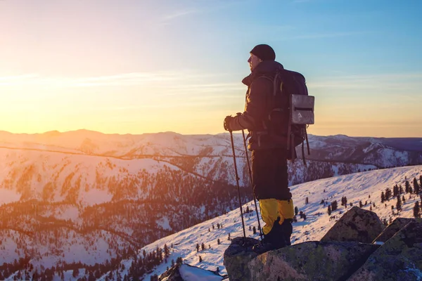 Hombre excursionistas de pie en la montaña nevada pico al atardecer — Foto de Stock