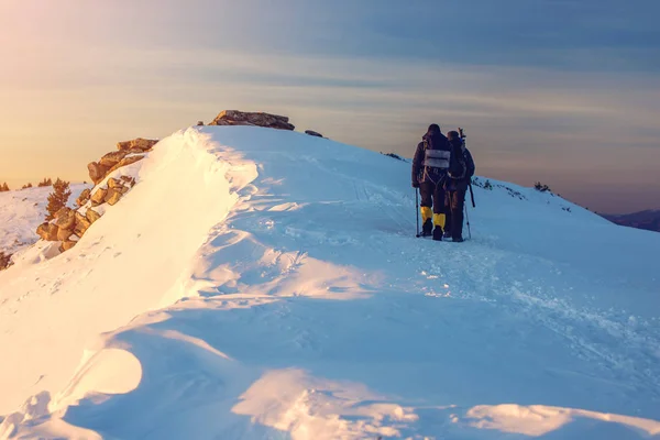 Karlı dağlardaki dön günbatımında seyahat yürüyüşçü — Stok fotoğraf