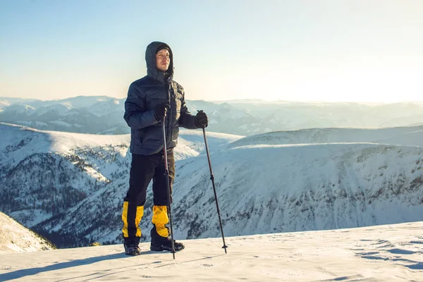 Gün batımında karlı dağ tepe üzerinde duran adam yürüyüşçü — Stok fotoğraf