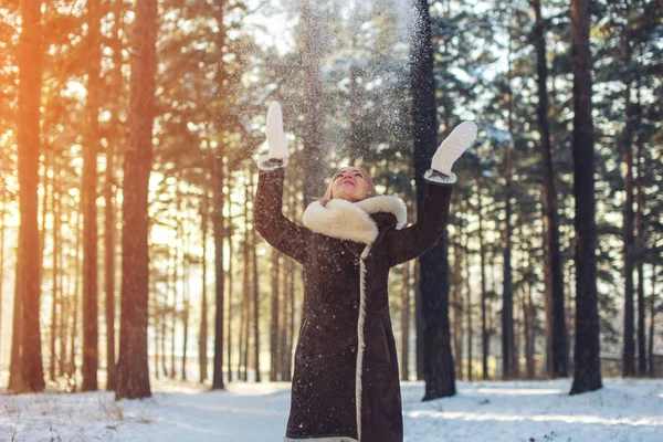 attractive woman throws up snow into the air at sunset