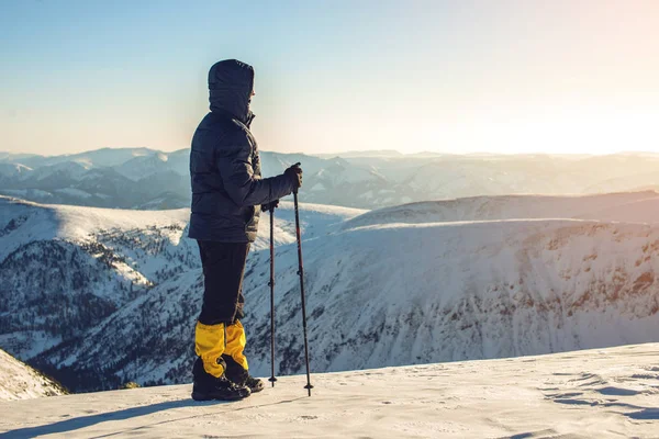 Gün batımında karlı dağ tepe üzerinde duran adam yürüyüşçü — Stok fotoğraf