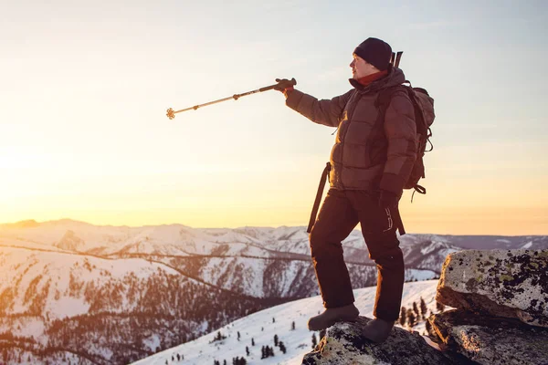 Escursionisti uomo in piedi sulla cima della montagna innevata al tramonto — Foto Stock