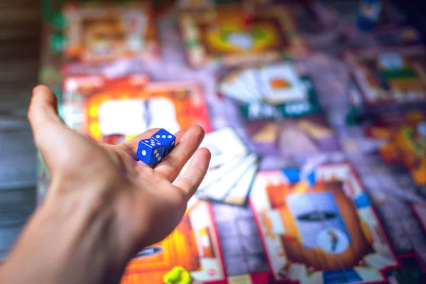 Hand wirft Würfel auf den Hintergrund von Brettspielen — Stockfoto