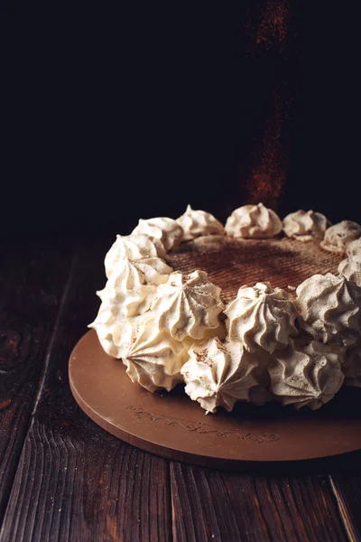 Белый торт Meringue, посыпанный какао на деревянный стол — стоковое фото