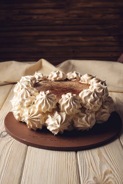 Белый торт Meringue, посыпанный какао на деревянный стол — стоковое фото