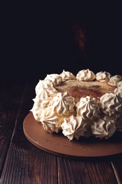 Белый торт Meringue, посыпанный какао на деревянный стол — стоковое фото