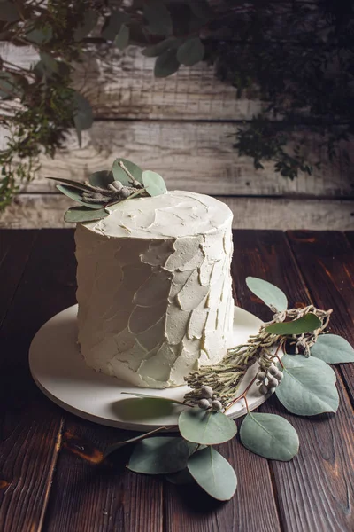 Белый крем торт украшен зелеными листьями — стоковое фото