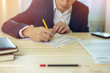 Adam işadamı belgeleri bir kalemle işaretler.