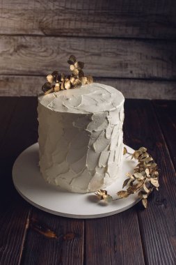 bir şube altın yapraklarla süslenmiş beyaz kremalı pasta