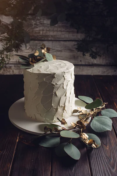 Pastel de crema blanca decorada con una rama con hojas de oro — Foto de Stock