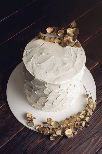 Bolo de creme branco decorado com um ramo com folhas de ouro — Fotografia de Stock