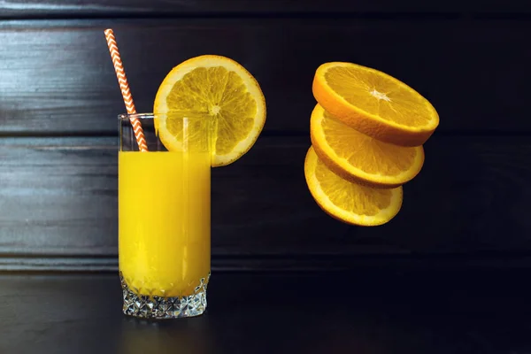 Ποτήρι χυμό πορτοκαλιού με φέτες πορτοκάλι που κρέμεται στον αέρα — Φωτογραφία Αρχείου