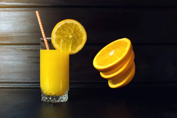 Glass of orange juice with sliced orange hanging in air