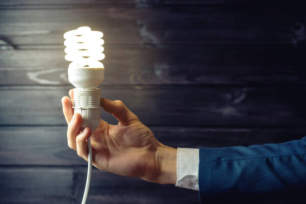 Hand holds a glowing light bulb. Creative idea in business