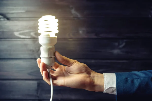 La mano sostiene una bombilla brillante. Idea creativa en los negocios — Foto de Stock