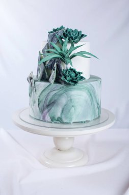 Wedding cake decorated like a stone marble with green flowers clipart