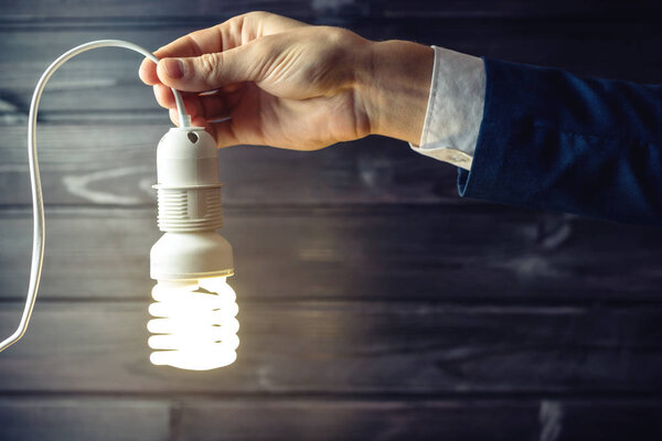 Hand holds a glowing light bulb. Creative idea in business