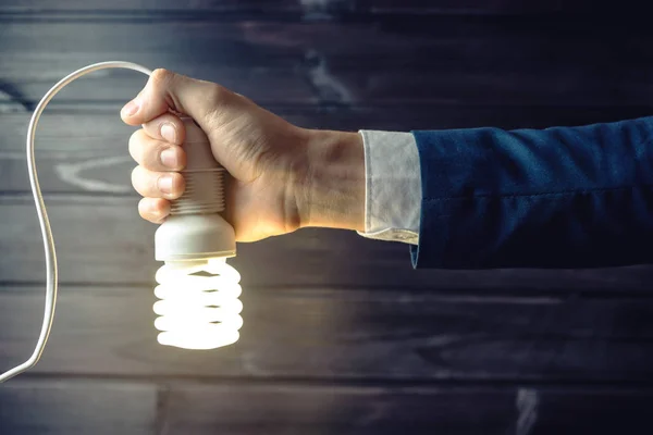 La mano sostiene una bombilla brillante. Idea creativa en los negocios — Foto de Stock