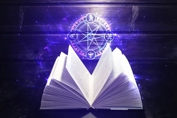 Книга на столе выходит свет и волшебный знак — стоковое фото