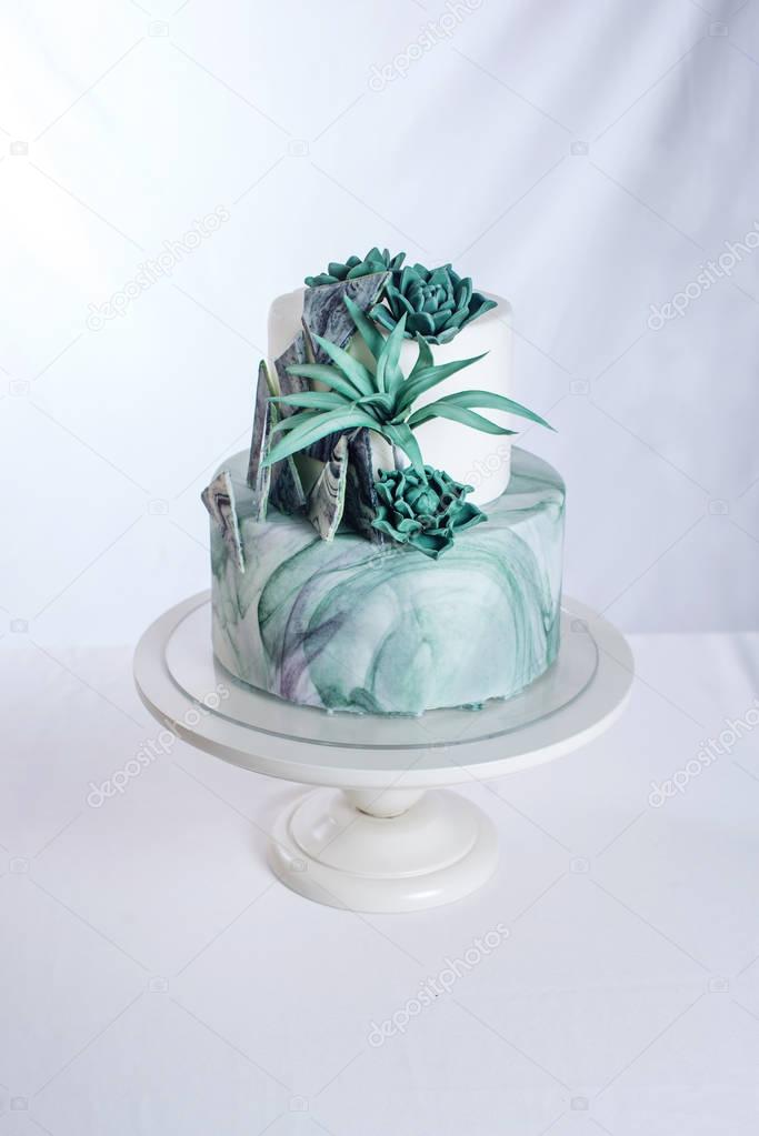 Wedding cake decorated like a stone marble with green flowers
