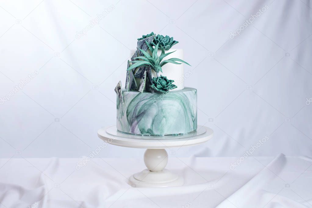 Wedding cake decorated like a stone marble with green flowers
