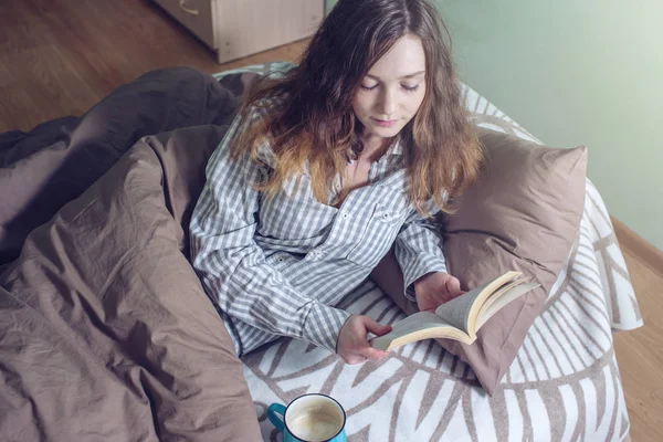 Jolie fille lisant un livre tout couché dans le lit — Photo