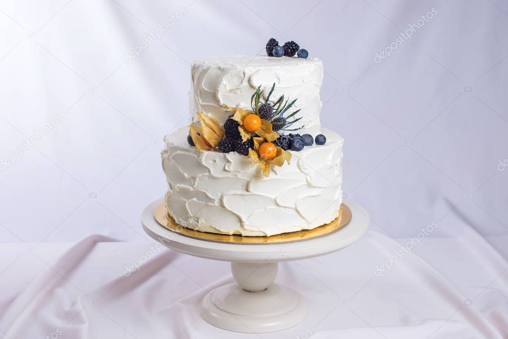 two-tiered white cream cake decorated with berries