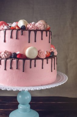 Pembe kek çilek, şekerleme ve macaroons üstte rustik.