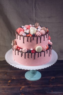 Pembe kek çilek, şekerleme ve macaroons üstte rustik.