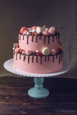 Pembe kek çilek, şekerleme ve macaroons üstte rustik.