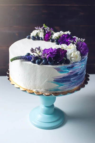 Colorful wedding cake with lovely purple flowers and blueberries