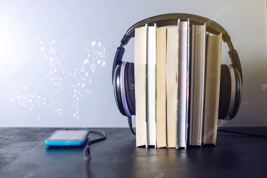 Headphones on books and flying notes. The concept of audiobooks