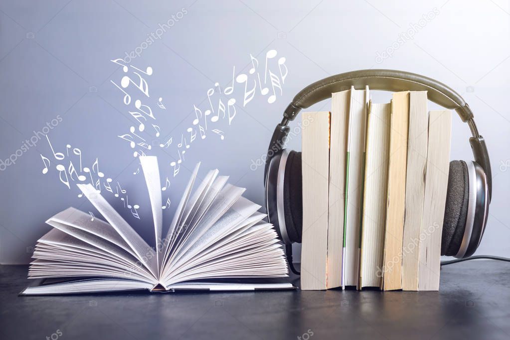 Headphones on books and flying notes. The concept of audiobooks