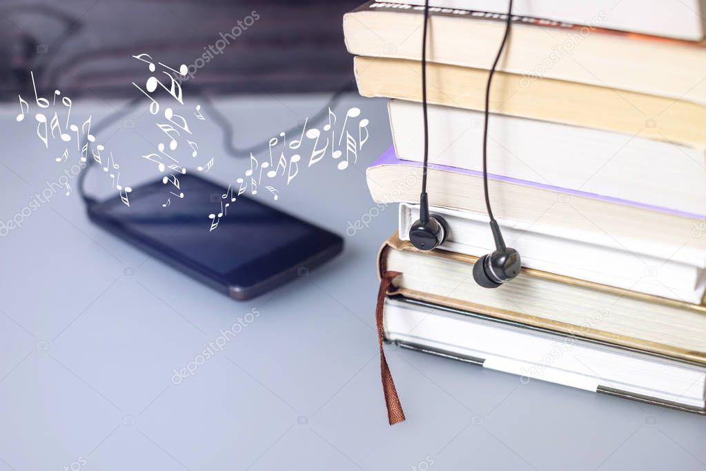Headphones on books and flying notes. The concept of audiobooks