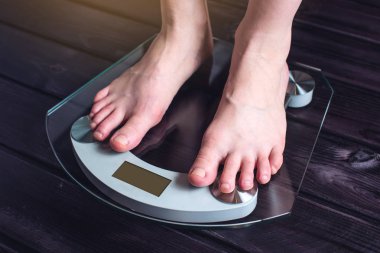 Kadın ayakları kilo kontrolü için elektronik teraziler tutuyoruz