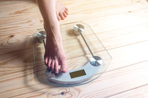 Female feet standing on electronic scales for weight control