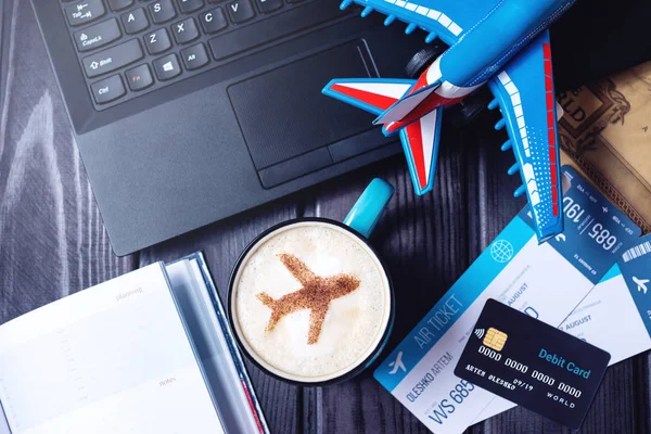 Laptop, plane tickets, coffee, credit card lies on the table