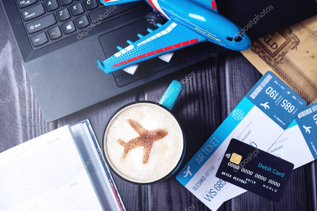 Laptop, plane tickets, coffee, credit card lies on the table